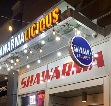 Shawarmalicious storefront at night with its lit sign on 17th Ave SW