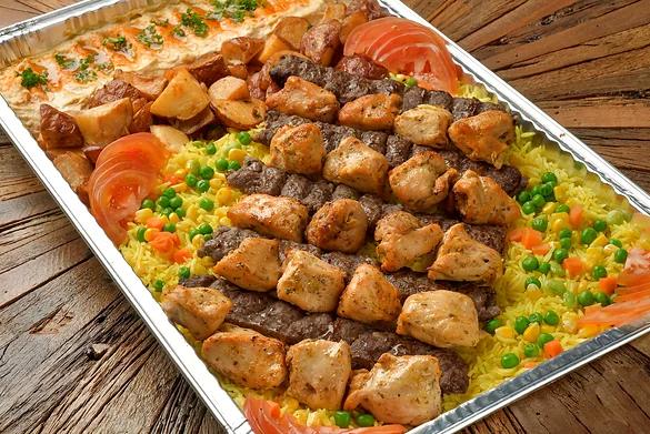 Tray of kabab and shish tawook skewers over rice with garlic potatoes