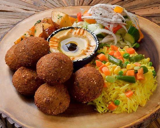 Falafel with hummus, yellow rice and garlic potatoes on a wooden board