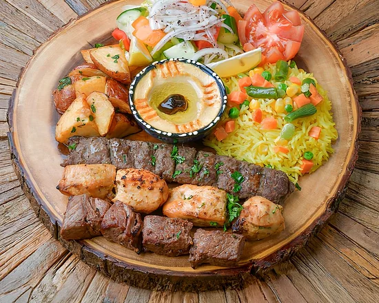Grilled kabab and shish tawook skewers with rice and hummus on a wooden board