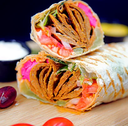 Beef donair wrap cut in half with garlic sauce and hot sauce