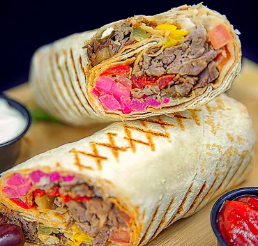 Mixed beef and chicken shawarma wrap cut in half with garlic sauce