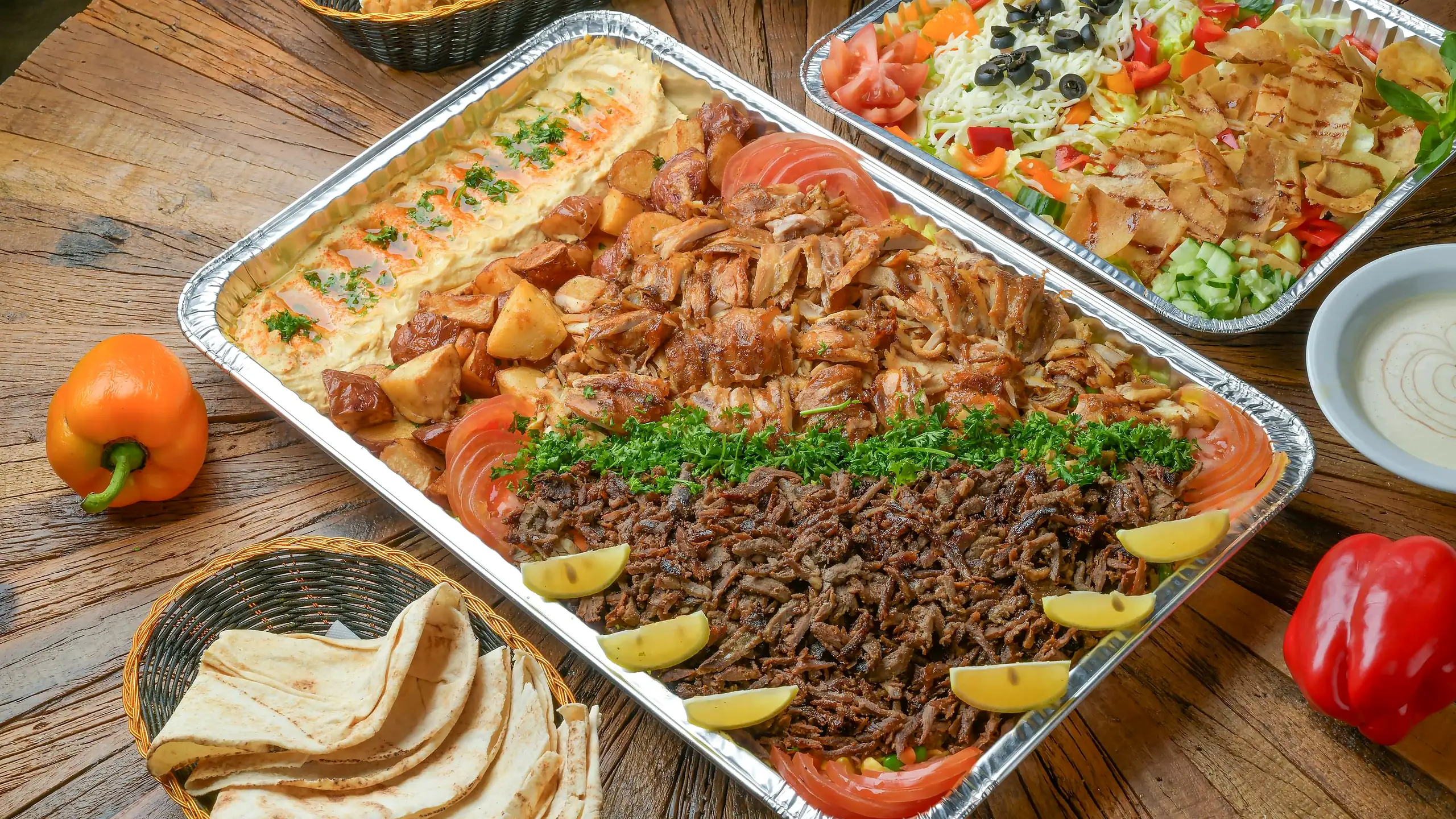 Shawarma platter tray with chicken and beef shawarma, hummus and garlic potatoes, with pita and a salad tray