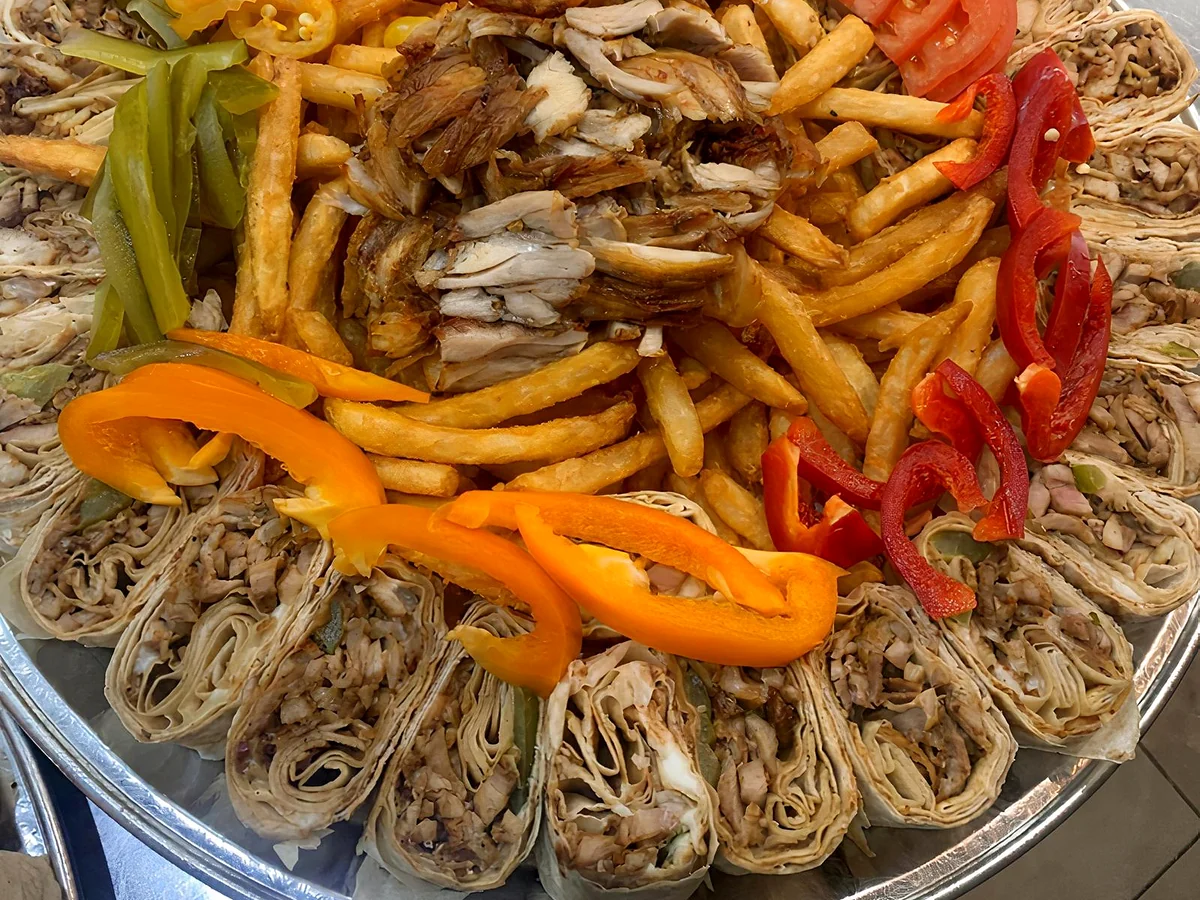 Platter of shawarma bites ringed around fries, sliced shawarma, peppers and pickles
